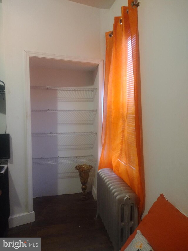 bedroom featuring radiator heating unit and dark hardwood / wood-style floors