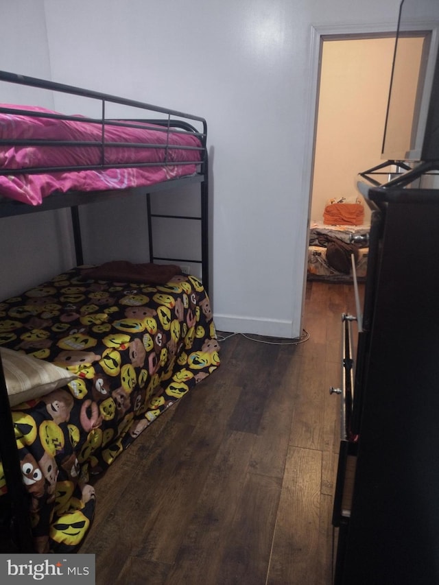 bedroom with black refrigerator and dark wood-type flooring