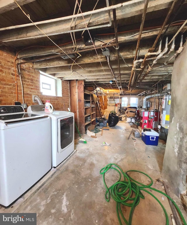 basement with water heater, brick wall, and separate washer and dryer