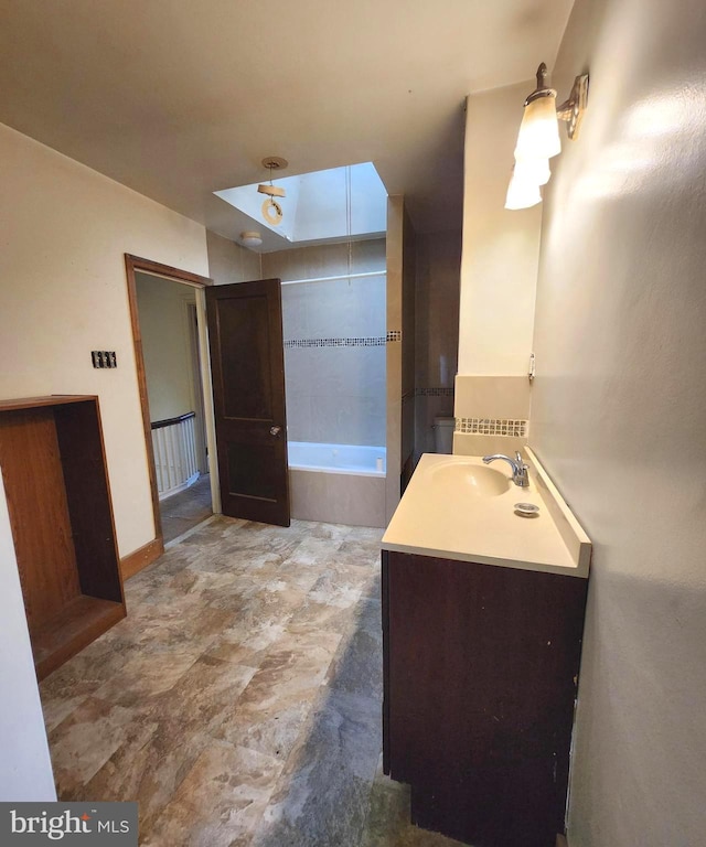 bathroom featuring vanity, a skylight, and a relaxing tiled tub