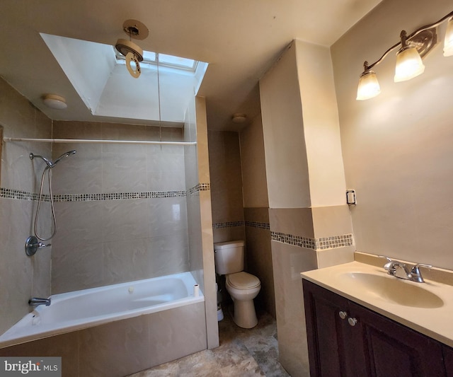 full bathroom with a skylight, vanity, tiled shower / bath combo, and toilet