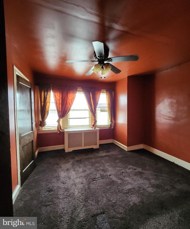 carpeted empty room featuring ceiling fan and radiator heating unit