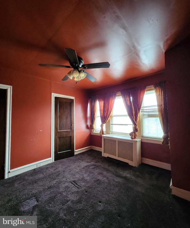 carpeted empty room with radiator and ceiling fan