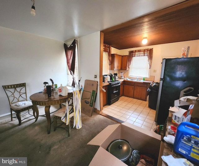 kitchen with refrigerator, light colored carpet, and black gas range