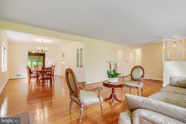 living room with visible vents, light wood finished floors, a notable chandelier, and baseboards