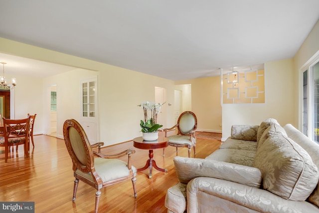living room with a notable chandelier, baseboards, and wood finished floors