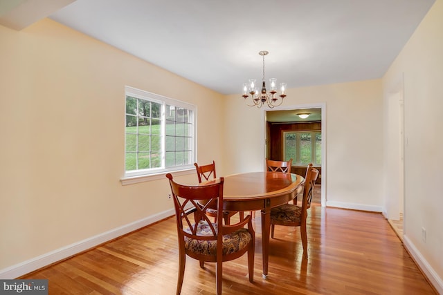 dining area featuring light wood-type flooring and an inviting chandelier