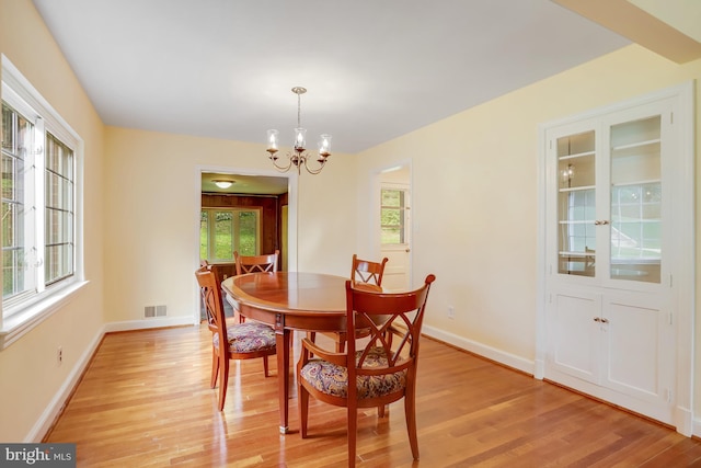dining area with light wood-style flooring, an inviting chandelier, baseboards, and visible vents