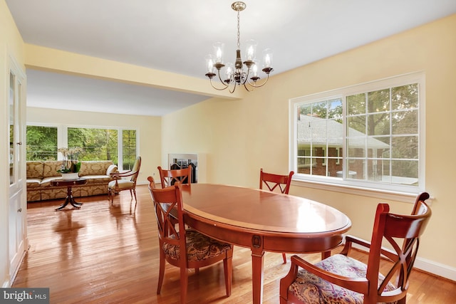 dining area with baseboards, a notable chandelier, and light wood-style floors