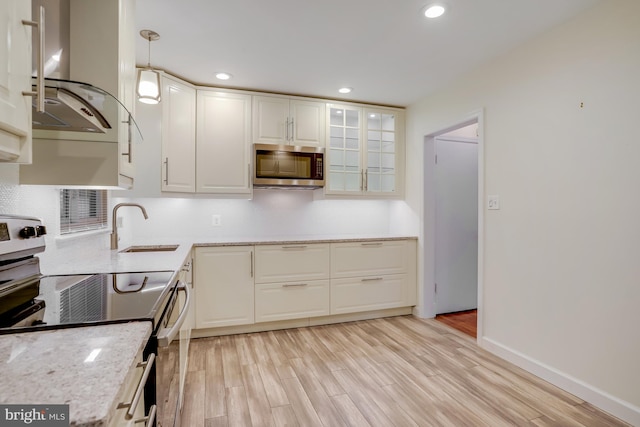 kitchen featuring hanging light fixtures, range with electric stovetop, white cabinetry, and light hardwood / wood-style flooring