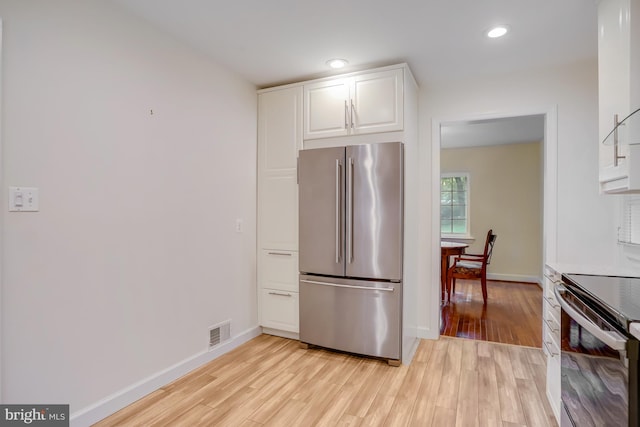 kitchen featuring stainless steel appliances, white cabinetry, and light wood-type flooring