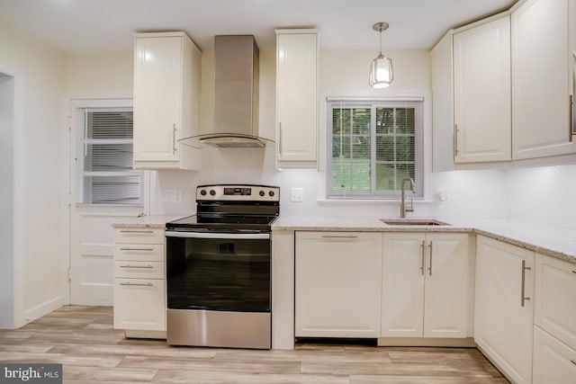 kitchen featuring stainless steel range with electric cooktop, light stone counters, wall chimney range hood, hanging light fixtures, and sink