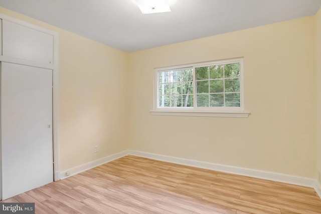 spare room with baseboards and light wood-type flooring
