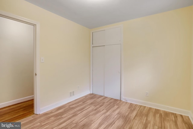 unfurnished bedroom with visible vents, baseboards, a closet, and light wood-style floors