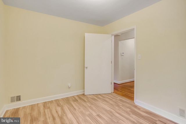 empty room featuring visible vents, light wood-type flooring, and baseboards