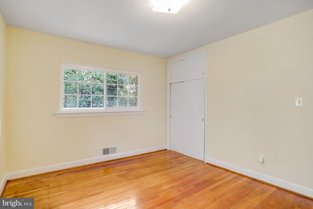 empty room with visible vents, light wood-type flooring, and baseboards