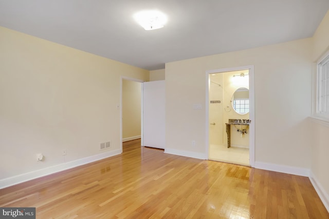 unfurnished bedroom with light hardwood / wood-style floors and ensuite bath