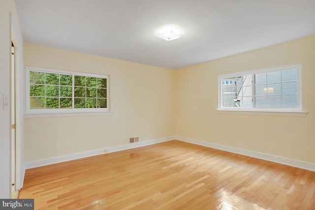 unfurnished room featuring light wood finished floors, visible vents, and baseboards