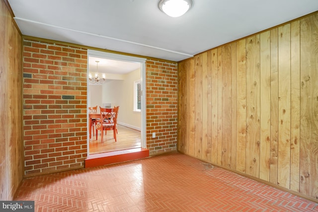 unfurnished room with wood walls and a chandelier