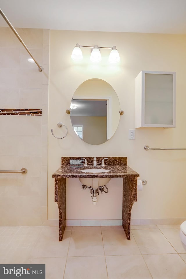 full bath with a sink, tile patterned floors, a tile shower, and toilet