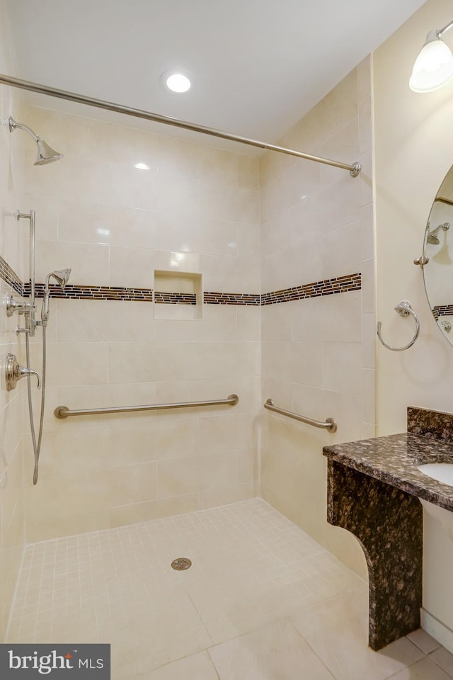 bathroom with tiled shower and vanity