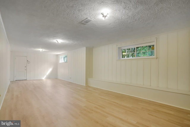 basement with a textured ceiling, wood finished floors, and visible vents