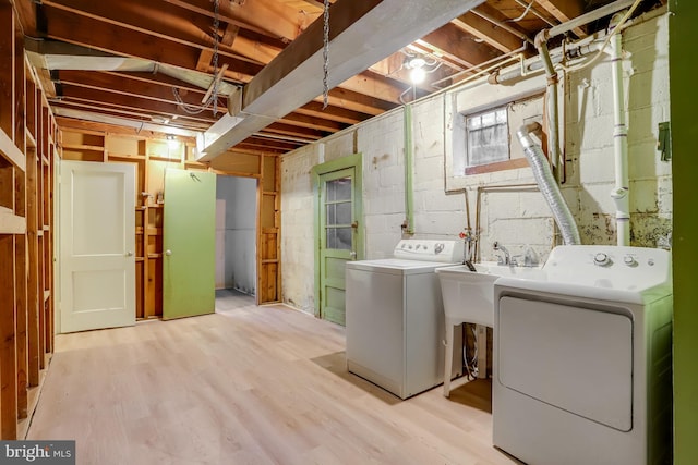 washroom with light wood-type flooring, washing machine and dryer, and sink