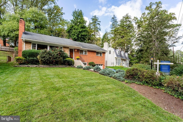 ranch-style home with brick siding, an attached garage, a chimney, and a front lawn