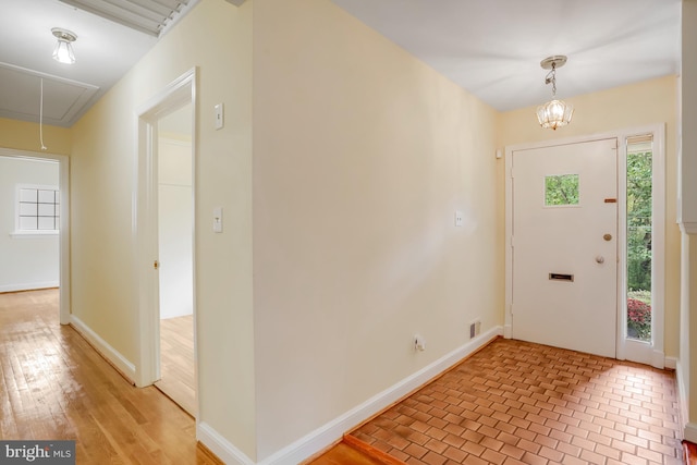 entrance foyer with light wood-style flooring, baseboards, visible vents, and a notable chandelier