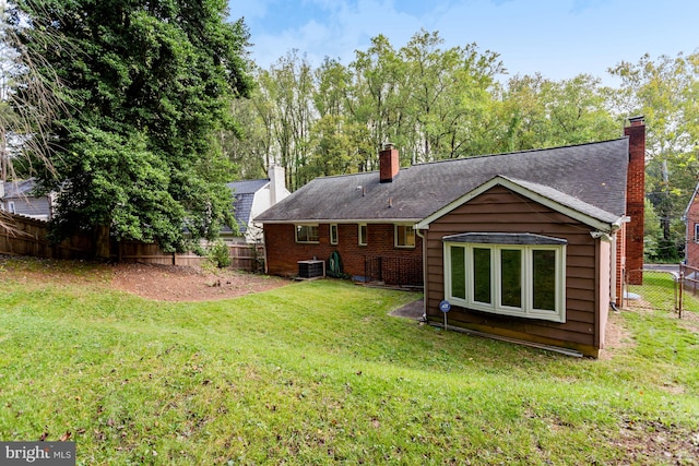 rear view of house featuring central AC unit and a yard