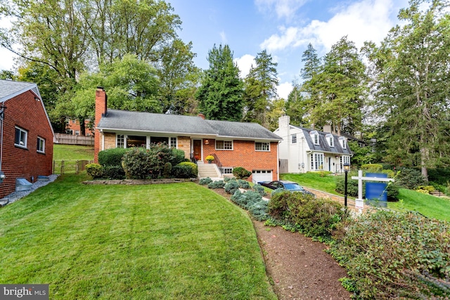 view of front of property with a front yard, fence, brick siding, a chimney, and a garage