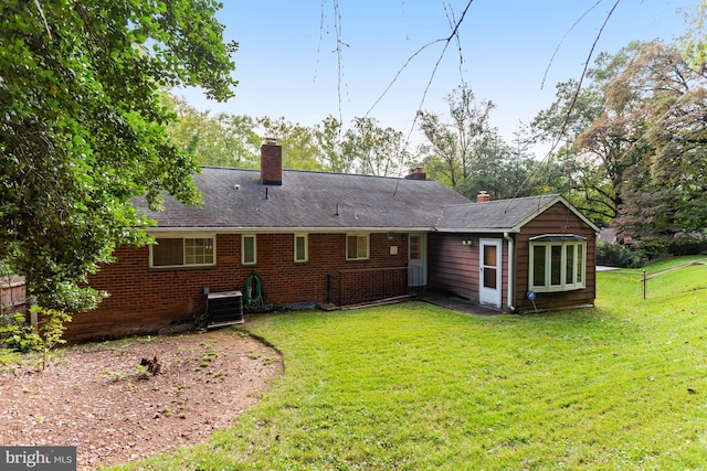 back of house featuring central air condition unit and a yard