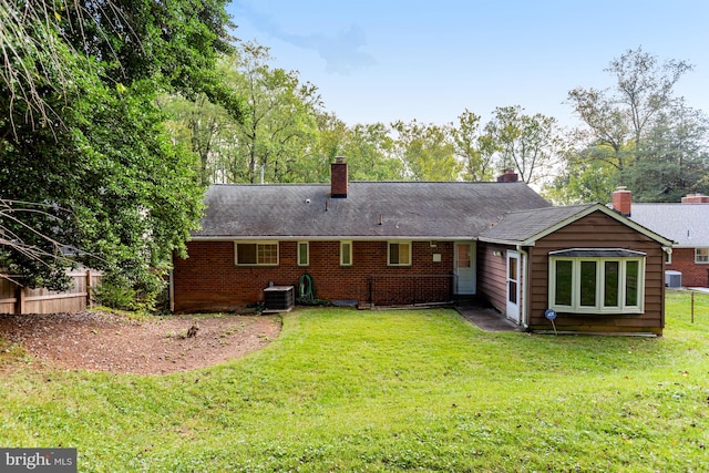 rear view of property featuring central air condition unit and a yard