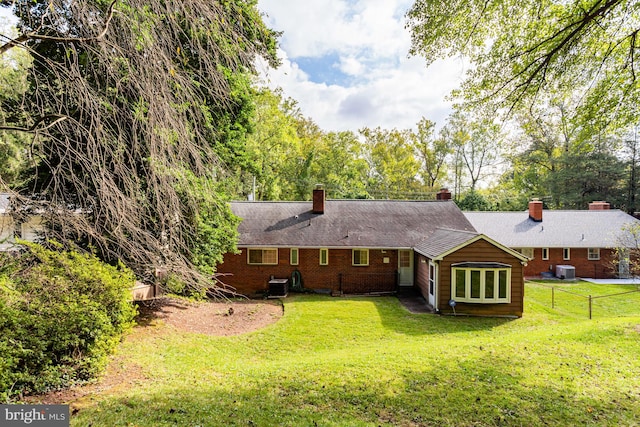 back of property with central air condition unit and a yard