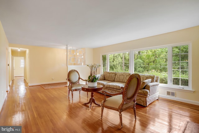living room featuring visible vents, light wood-style flooring, baseboards, and a healthy amount of sunlight