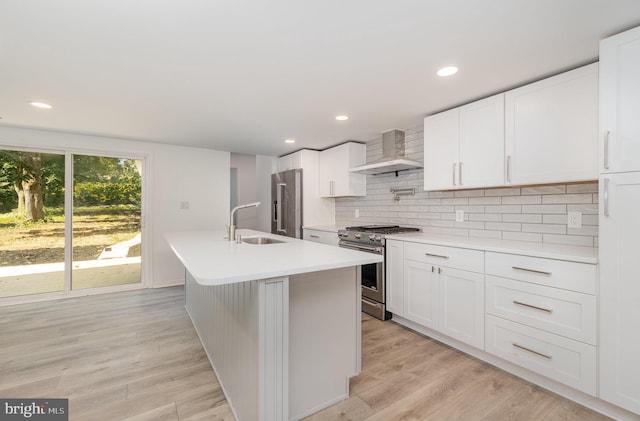 kitchen with light wood-style flooring, wall chimney exhaust hood, high end appliances, and a sink