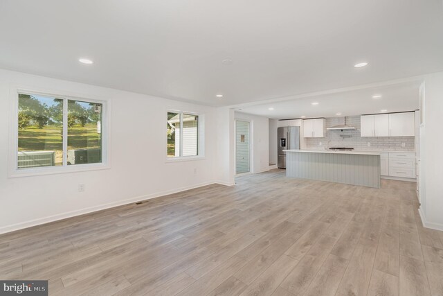 unfurnished living room with recessed lighting, baseboards, and light wood-style floors