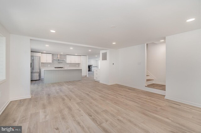 unfurnished living room featuring stairs, recessed lighting, and light wood finished floors