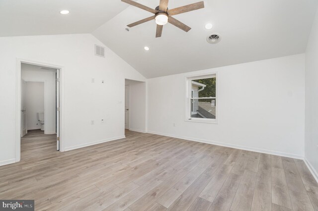 empty room featuring visible vents, lofted ceiling, and light wood-style flooring