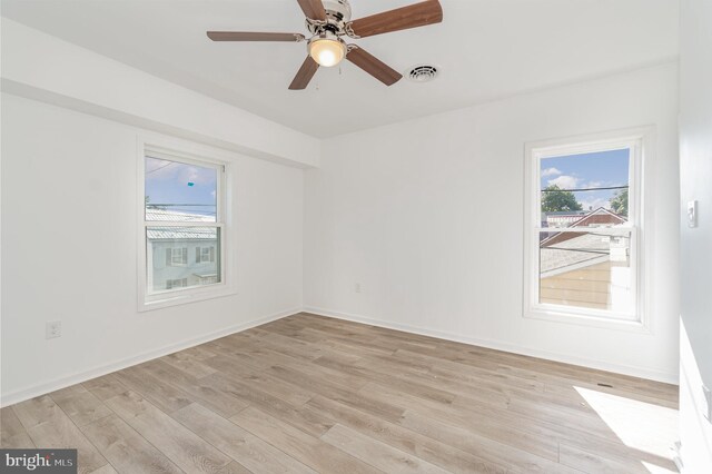 empty room with visible vents, a healthy amount of sunlight, light wood-style flooring, and baseboards