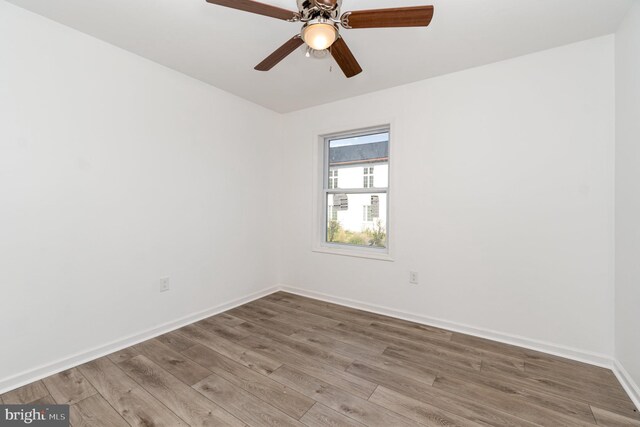 spare room featuring ceiling fan, baseboards, and wood finished floors