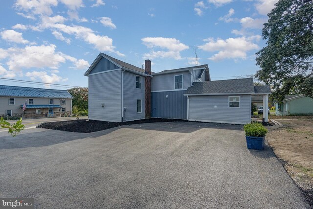 exterior space with aphalt driveway and roof with shingles