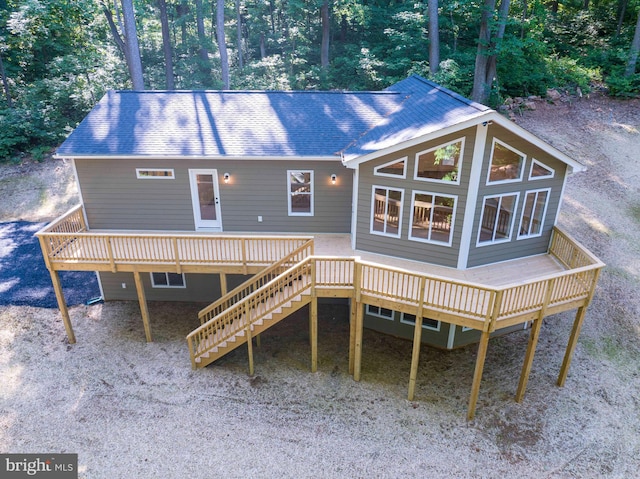 back of house featuring a shingled roof, a wooden deck, and stairs