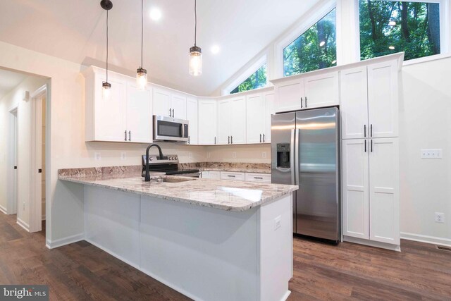 kitchen featuring hanging light fixtures, light stone countertops, appliances with stainless steel finishes, dark hardwood / wood-style floors, and kitchen peninsula