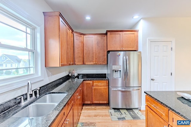 kitchen featuring stainless steel fridge with ice dispenser, a healthy amount of sunlight, dark stone countertops, and sink