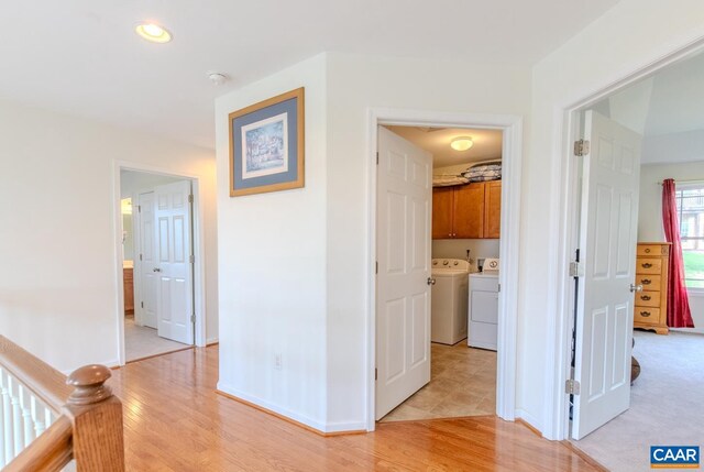 corridor with light wood-type flooring and washer and dryer