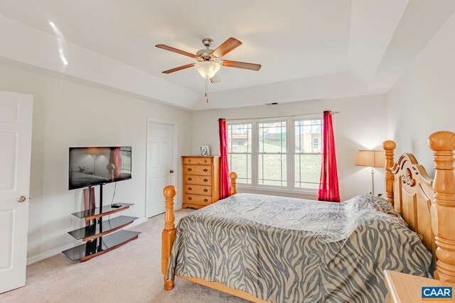 carpeted bedroom featuring ceiling fan and a raised ceiling