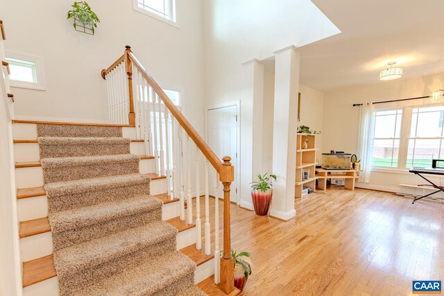 stairs featuring plenty of natural light, hardwood / wood-style floors, and decorative columns