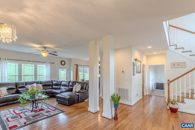 living room with light wood-type flooring and ceiling fan with notable chandelier