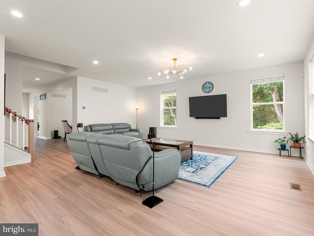 living room with an inviting chandelier, light hardwood / wood-style floors, and a healthy amount of sunlight